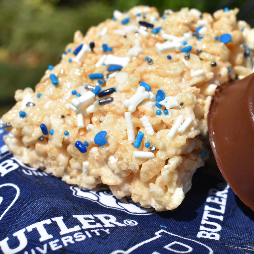 Crispy rice treat with blue and white sprinkles and a chocolate covered item on a Butler University towel.