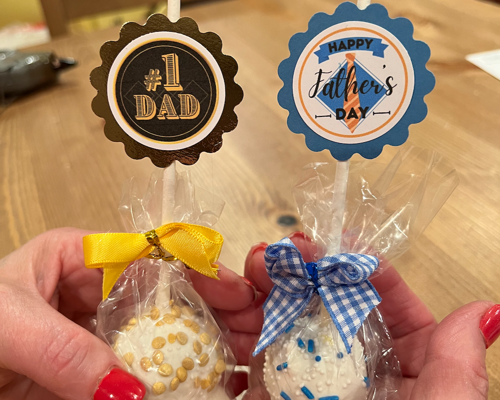 Two small decorated items with Father's Day-themed tags held by a person.