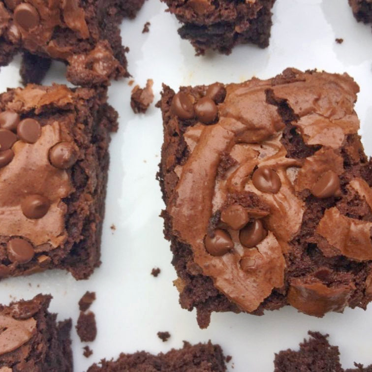 A close up of multiple chocolate brownie pieces with chocolate chips on a white tray.