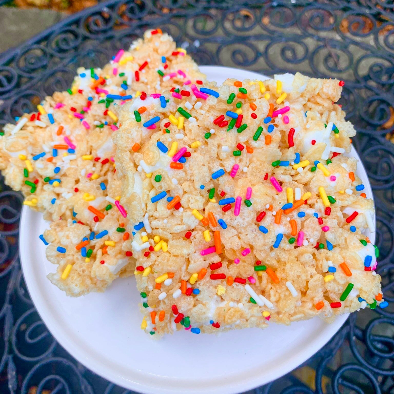Two crispy rice treats with colorful sprinkles on a white plate.