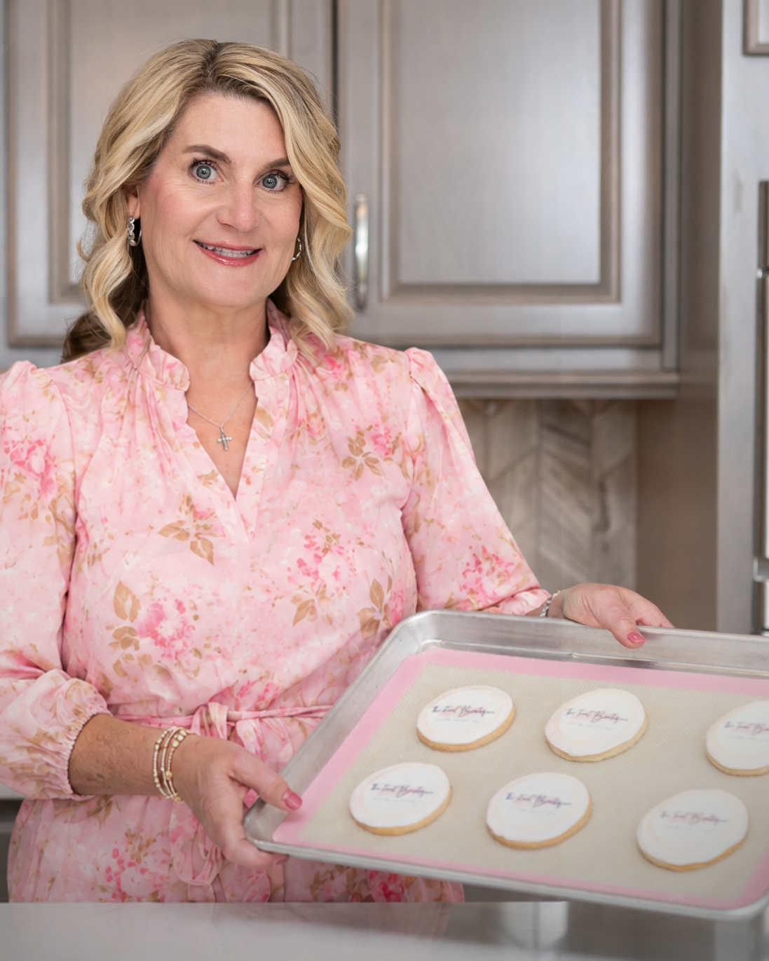 Woman in a kitchen holding a tray of cookies