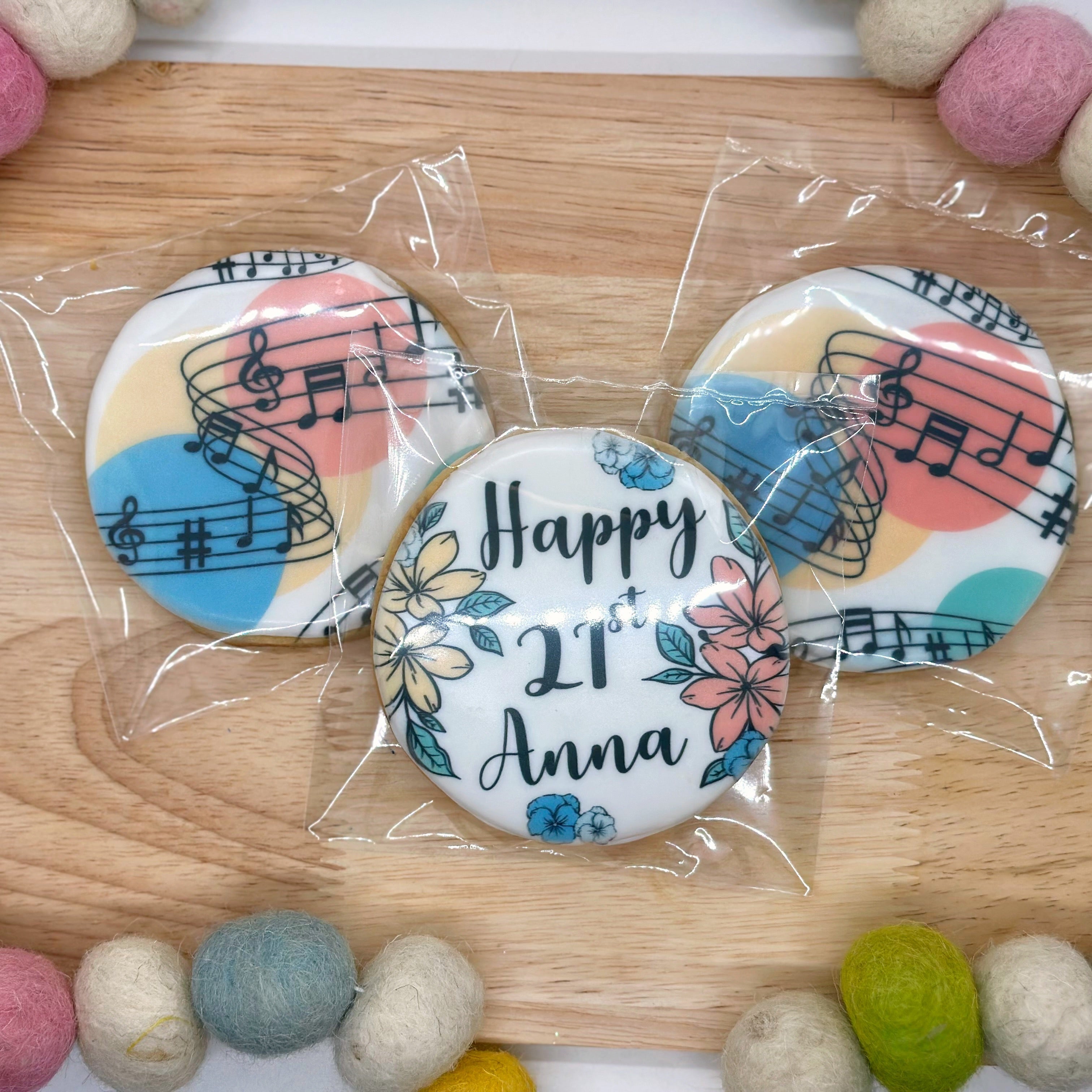 Decorative cookies with musical notes and 'Happy 21st Anna' text on a wooden board.
